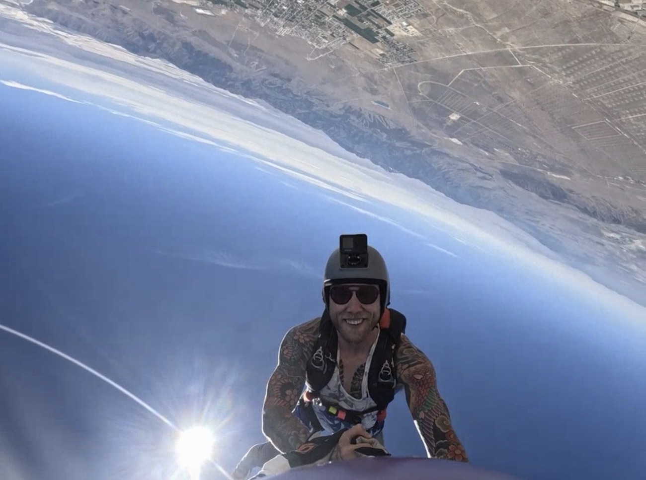 Brock in freefall, grinning at the camera with the horizon tilted behind him